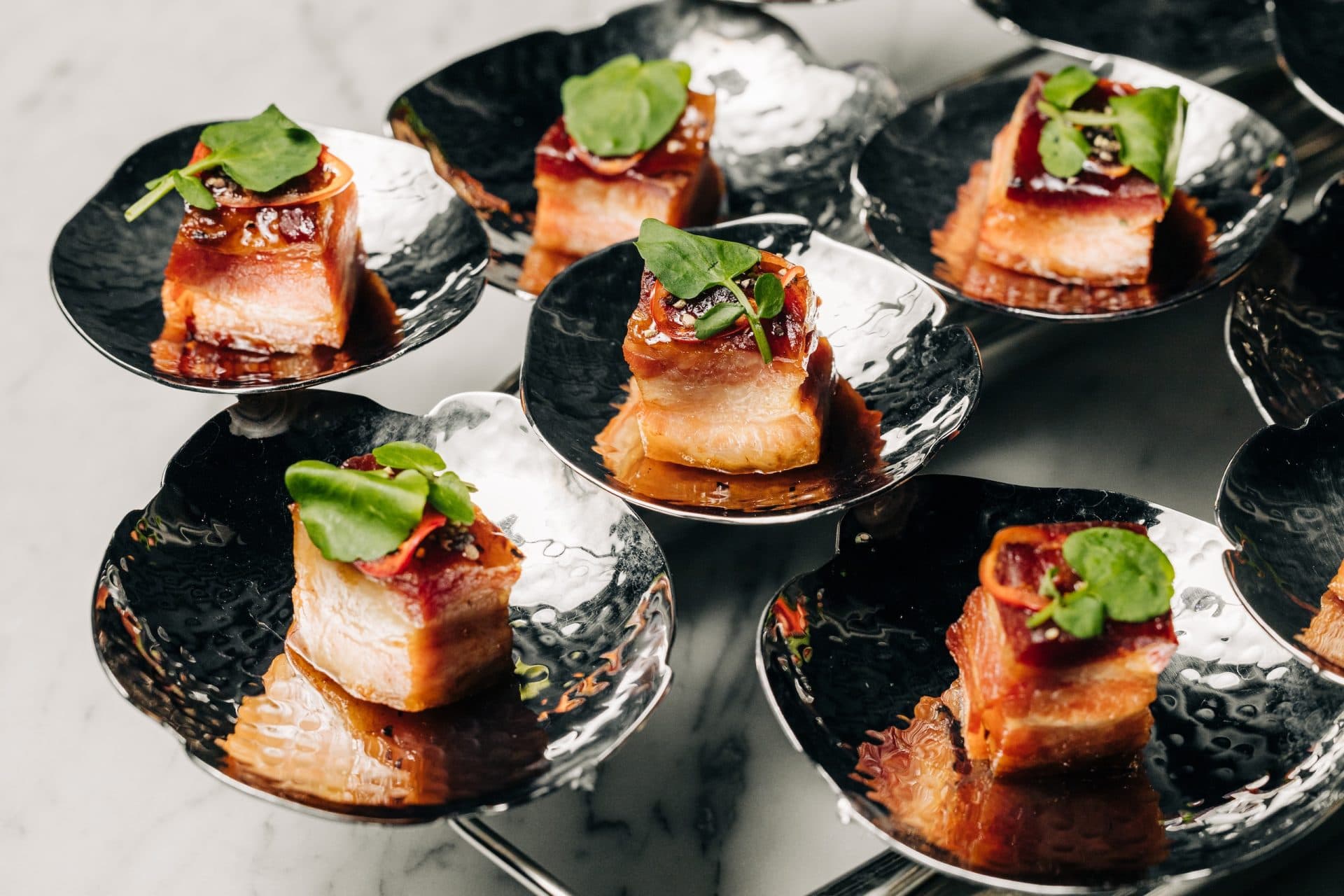 Pieces of bourbon and vanilla glazed bacon on a silver serving platter at the Meta APEX Center, a premier event venue in Las Vegas